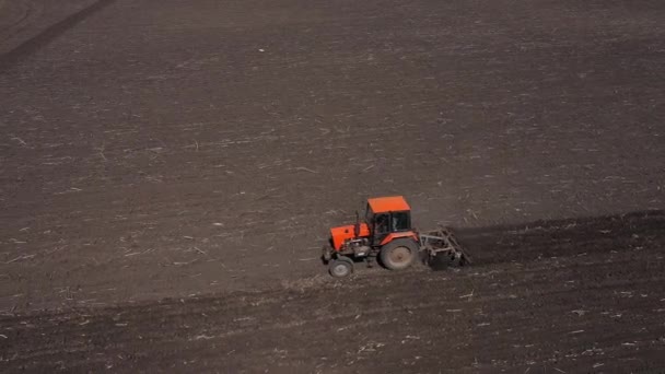 Ploughing red tractor at field cultivation work aerial view — Stockvideo