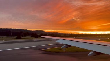 Güneş batarken havaalanı üzerinde son yaklaşım turuncu ışık çizgileri kanat görüşü kurumsal seyahat konseptini bulutlandırıyor. Yüksek kalite 4k görüntü