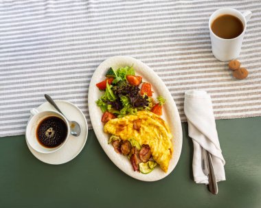 Taze marul ve domates salatasıyla birlikte sotelenmiş sebzeler ve pastırma üzerine sarılmış yumuşak yumurta omletinden sabah yemeği..