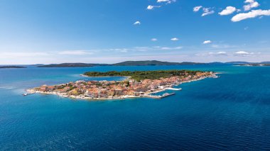Sibenik Hırvatistan yakınlarındaki Krapanj ada köyünün turkuaz Adriyatik suyu, marina, çatıları ve yaz gökyüzü ile insansız hava aracı panoraması. Yüksek kalite fotoğraf