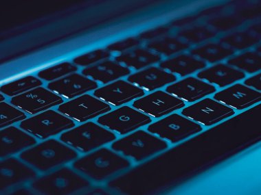 Dizüstü bilgisayarın yakın görüntüsü mavi arka plan ışığıyla aydınlatılmış