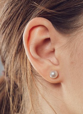 Küpeli genç bir kadının kulağının yakın çekimi..