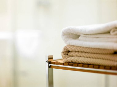 Modern banyo ortamında bambu rafına düzgünce dizilmiş üç havlu.