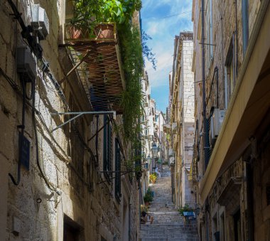 Yeşil başlıklı eski taş binalarla çevrili dar sokaklar.