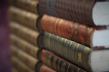 Ahşap bir yüzeyde duran bir yığın eski kitap..