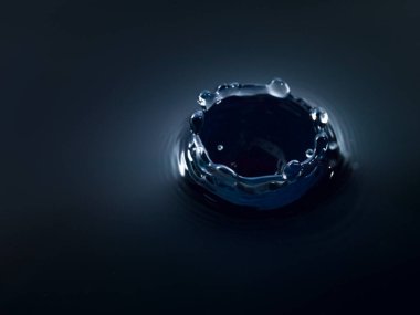 Pürüzsüz siyah bir yüzey üzerinde duran küçük siyah bir nesne..