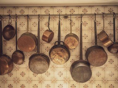 Mutfak duvarında çeşitli tencere ve tavalar asılı..