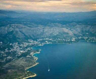 Tepeler ve su ile kıyı manzarası.