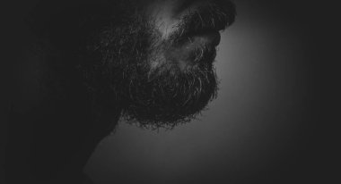 Sakallı ve karanlıkta gölgeli yüzlü bir adam..