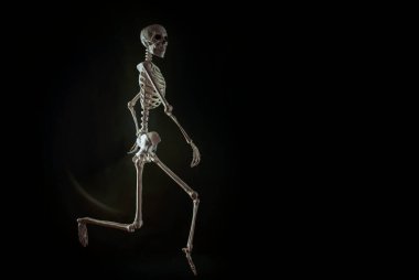 Karanlık bir arkaplanda koşan bir iskelet figürü.