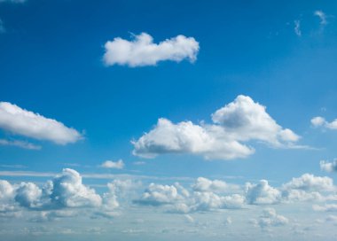 Açık mavi gökyüzünde süzülen beyaz bulutlar.