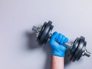 Eldivenli bir elle dambıl kaldıran kişi.