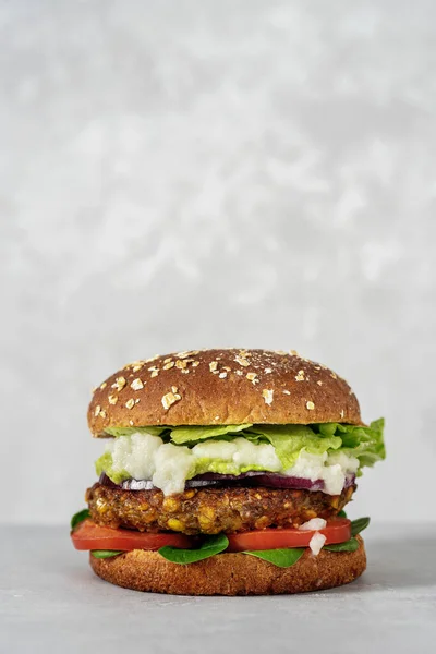 Delicious vegan burger with lentils and vegetables on light gray background. Vegan food concept. Copy space