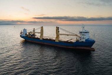 Günbatımında sakin Baltık Denizi 'nde yelken açan genel bir kargo gemisi, bir gemi..