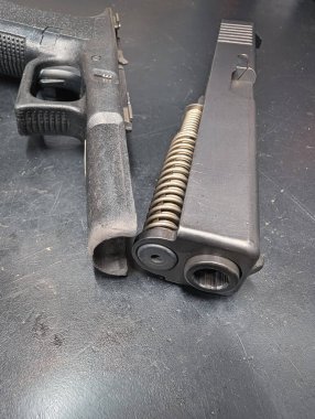 Eski, kirli, yarı otomatik bir tabanca temizlik ve bakım için sökülmüş, kaydırak ve çerçevesinde görünür karbon karışımı.