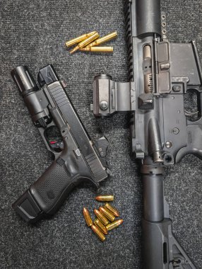 15 Ekim 2025, Baltık - Taktiksel aksesuarlı Glock 19 ve AR-15 karabinası, her ikisi de kırmızı nokta çarpışma gözlükleriyle donatılmış, cephaneyle sergileniyor..