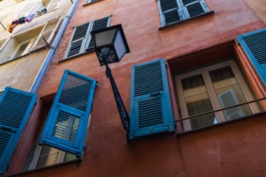 Nice, Fransa 'da canlı mavi panjurları ve klasik bir sokak lambası olan geleneksel eski bir binanın alçak açılı görüntüsü..