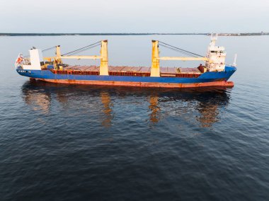 Alacakaranlıkta sakin Baltık Denizi 'nde yüzen sarı vinçli endüstriyel bir kargo gemisinin yüksek açılı drone görüntüsü..