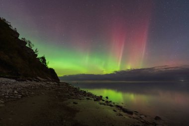 Güzel Kuzey Işıkları (Aurora Borealis) Estonya 'nın Paldiski yarımadasındaki Baltık Denizi kıyısında yeşil ve pembe dans eder..