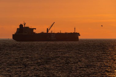 Bir gemiden gemiye sığınak operasyonunun silueti. Bir yakıt tankeri gün batımında Baltık Denizi 'nde daha küçük bir gemiyle demirlemiş..