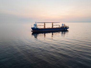 Güzel bir alacakaranlık gökyüzü ve ufuk altında açık, sakin Baltık Denizi 'nde yelken açan bir kargo gemisinin geniş hava aracı görüntüsü..