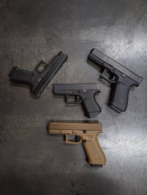 Baltık Devletleri 25 Ekim 2025. Dört farklı Glock tabanca koleksiyonu, G48, G19X, G21 ve G43 modelleri, karanlık bir endüstriyel yüzeye yerleştirilmiştir..