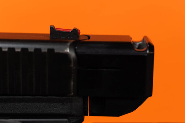 Экстремальное крупным планом макрофото высокого видимости красного переднего прицела пистолета и намордника компенсированного слайда.