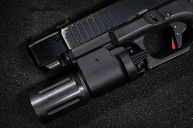 Namlu freni, silah ışığı ve kırmızı özel tetiğe sahip çok özelleştirilmiş bir taktik tabancanın yakın çekimi..