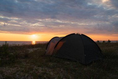 Vahşi Kamp Çadırı Estonya kıyılarında dramatik bulutlar ve okyanus manzaralı, Huzurlu Baltık Denizi Doğa Sahnesi.