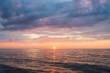 Estonya 'nın sakin körfezi üzerinde güneşli ve dramatik bulutlarla güzel renkli bir gün batımı..