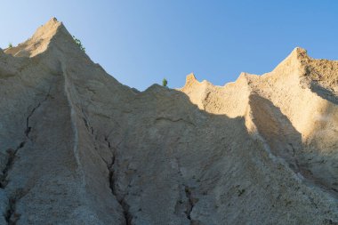 Açık mavi gökyüzüne karşı kireçtaşı ocağının ya da kum dağının güneşli tepeleri ve dokulu yamaçları..