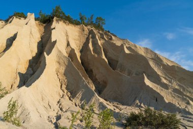 Güneşli bir havada açık mavi gökyüzünün altında terk edilmiş bir taş ocağının dramatik kum kayalıkları ve vadileri aşındı..