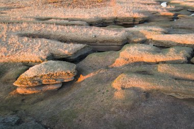 Estonya 'daki ilkbahar karst manzarasının hava aracı görüntüsü, katmanlı kaya oluşumları sıcak günbatımı ışığı ile aydınlatılıyor..