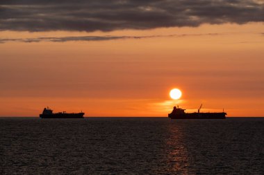 Estonya açıklarında güzel bir turuncu gün batımında Baltık Denizi ufkunda iki kargo gemisi silueti.. 