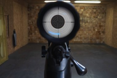 İçerideki atış poligonunda hedef tahtasını optik dürbünle hedefleyen ilk kişi..