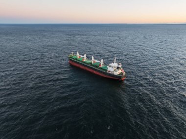 Gün batımında Baltık Denizi 'nin derin mavi sularında ilerleyen büyük bir yük gemisinin çarpıcı hava aracı görüntüsü..