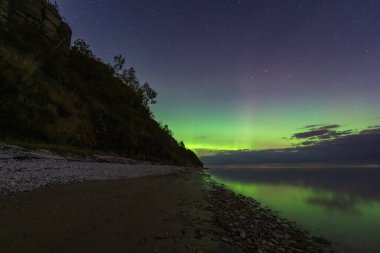 Yeşil Aurora Borealis, Estonya Paldiski 'deki Pakistan Yarımadası' nın kireçtaşı kayalıklarının ve plajlarının üzerinde gece gökyüzünü aydınlatıyor..