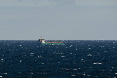 Yeşil kargo gemisinin Baltık Denizi ufkunun engebeli mavi sularında yelken açtığı uzak bir manzara..