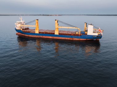 Baltık Denizi sularına demirlemiş vinçleri olan büyük boş bir kargo gemisinin insansız hava aracı görüntüsü..