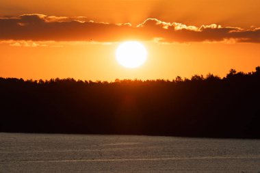 Baltık Denizi 'nin engin, karanlık engin üzerinde canlı turuncu yaz gündoğumu. Güneş, sık bir orman ufkunun altında..