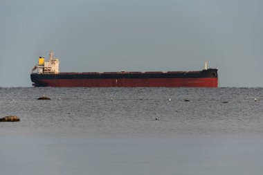 Büyük bir gemi, siyah ve kırmızıya boyanmış, Estonya kıyıları yakınlarındaki sakin Baltık Denizi 'nin ufkunda, yumuşak ve berrak bir gökyüzünün altında demirlemiş..