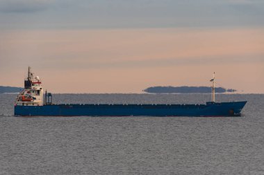 Kargo gemisi ya da yük gemisi, Estonya 'nın sakin sularında alacakaranlıkta, ufukta adalarla birlikte yelken açıyor..