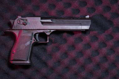 Büyük kalibreli, yarı otomatik, koyu dokulu arka planda ev güvenliği kavramları için profesyonel kırmızı stüdyo ışıklandırması olan bir tabanca..