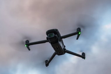 Günbatımında gökyüzünde uçan dönen pervaneli modern kuadkopter insansız hava aracı profesyonel hava fotoğrafçılığı ve video izleme için.