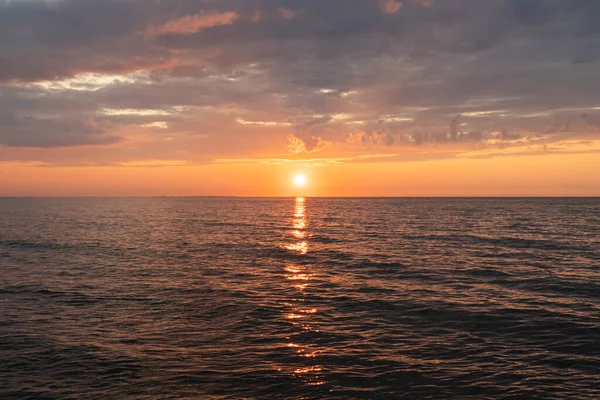 Estonya 'daki sakin Baltık Denizi ufkunun üzerinde güzel altın bir gün batımı dramatik bulutlar ve güneş ışığı suya yansıyor..