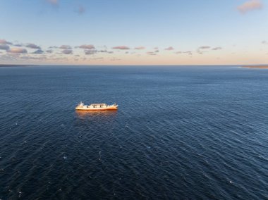 Tallinn, Estonya yakınlarındaki mavi Baltık Denizi 'nde gün batımında giden büyük bir kargo gemisinin hava görüntüsü..
