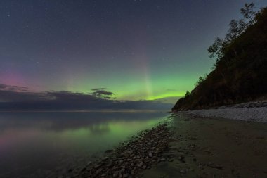 Kuzey Estonya, Paldiski yakınlarındaki Pakri Yarımadası 'ndaki Baltık Denizi kıyısında gece gökyüzünü aydınlatan nefes kesici Aurora Borealis..