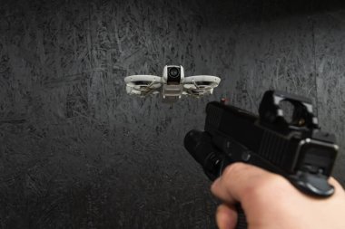 Kırmızı noktalı görüşlü taktik tabancaya ilk kişi bakış açısı karanlık arka plana karşı küçük bir gözetleme aracını hedefliyor..