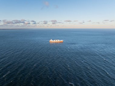 Estonya kıyıları yakınlarındaki mavi Baltık Denizi 'ne demir atmış büyük bir kargo gemisinin hava aracı görüntüsü. Gün batımı gökyüzünün altında..