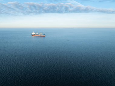 Geniş mavi Baltık Denizi 'ni açık bir gökyüzünün altında geçen büyük bir kargo gemisinin uzaktan kumandalı hava aracı görüntüsü..